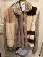 Front view of vintage coat showing patchwork fox fur panels and knitted collar and edges, satin lining visible inside.