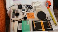 Overall photo showing all electronics including two Fitbits, chargers, earbuds, and accessories.