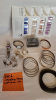 Photo shows entire lot with watches, rings, earrings, bangles, jewelry loupe, and nail polish strips laid out on white surface.