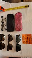 Overview of the four pairs of glasses and two cases showing different frame styles and textures of cases.