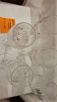 Top-down view of five crystal champagne flutes showing etched cut pattern inside bowls and starburst design on the bases.