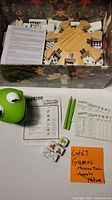 Mexican Train wooden hub with dominoes and instruction sheet, along with Muppets Yahtzee dice, pencils, and score sheets laid out.