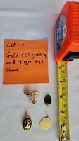 Photo showing four items: two pendants, one pair of earrings, and a loose stone on a white background with a tape measure and a note.