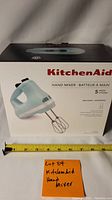 Front of the boxed KitchenAid hand mixer showing turquoise unit with 5 speed settings and Turbo Beater accessories.