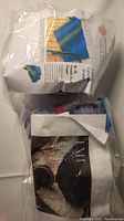 Photo of the knitting kit packaging and contents inside clear plastic bag, showing printed instructions and yarn for the Flower Catcher Shawl and fingerless mitts.
