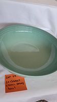 Full view of Le Creuset sage-colored serving bowl 13 inch diameter showing smooth glossy interior and outer glaze with a note identifying lot.