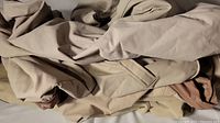 Beige and light brown fabric patio furniture covers all folded and wrinkled, showing material and color clearly.