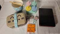 Full lot view showing all items together: Pusheen ramen bowl with chopsticks, beige Pusheen bento box, 3 popsicle molds, 3 curly straws, black bento box.
