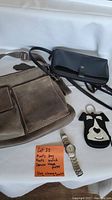 Roots grey distressed leather bag with adjustable strap, black Denver Hayes purse, dog-shaped change purse, and silver Roots wristwatch on white background