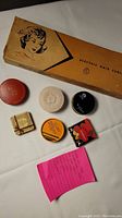 Electra-Curl electric hair curler box and 6 assorted compacts laid out with a note about lot contents