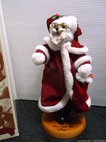 Full view of the Raikes Bears Classic Santa figurine dressed in red and white fur trim on a wooden base.