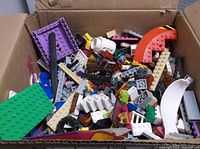 Box full of assorted loose LEGO bricks and parts, showing varied colors and piece types