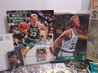 Photo showing 1991 Beckett Basketball Monthly magazine featuring Larry Bird, Latrell Sprewell action figure with card, and multiple smaller card packs and sheets laid out.