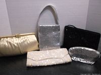 Set of five beaded and mesh handbags arranged on a surface, showing variety of colors and styles.