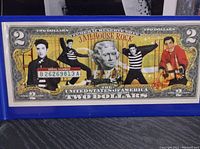 Close-up of framed commemorative $2 bill with Elvis Presley images, Jailhouse Rock theme, and serial number visible
