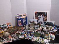Wide view of the bulk of the baseball card collection showing numerous cards spread out and stacked, figurines, and unopened packs.