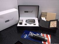 Full lot showing Baconi leather wallet, Ensemble 3-piece set with watch, tie and cufflinks, plus packaging boxes and unopened accessory.