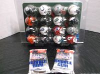 Full view of the mini NFL helmets arranged on a plastic standings tracker board along with two unopened bubble gum packs at the base.
