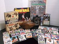 Display of New England Patriots memorabilia including trading cards spread out, vintage football, sticker album, book and magazine.