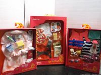 Three Our Generation doll outfit sets in original packaging: Goodnight Sleeptight bathrobe and spa set, Orders Up pizza apron and food set, Fun Day Sun Day swimsuit and beach set.