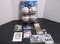 Four Rawlings collector baseballs in clear plastic packaging and a selection of baseball trading cards displayed spread around the package.