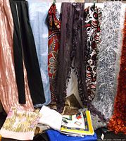 Twelve assorted scarves displayed revealing different textures, colors, and patterns including silky, lace, and textured fluffy scarves.