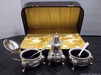 Full view of silver plated condiment set with saffron satin lined case
