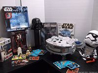 Full view of lot including plush Storm Trooper, giant Darth Vader Pez, Poe Dameron die cast figure, Pop Rey, melamine plate set, Star Wars themed ship, and some collectible cards and figures.
