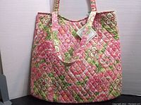Photo showing the front and side of the Vera Bradley Curvy Tote, quilted with a floral design in pink and green hues.
