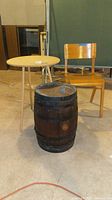 Photo showing a wooden chair, a small round wooden table, and a wine barrel in a basement setting
