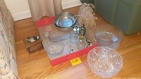 Overview photo showing all items in the lot on a table, including brass candle holders, crystal bowls, pewter bowls, glass votives, paperweight, ring holder with jewelry, and coasters.