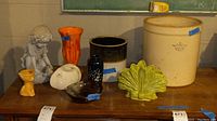Overview of all items on wooden surface including crocks, vases, bowls, and figurine. Items show crazing and need cleaning.