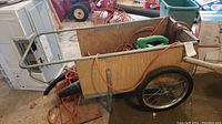 Wide view showing garden cart with wooden sides, metal frame, wheels, and orange extension cord inside