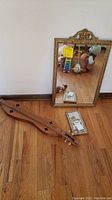Mirror, dulcimer, and tile arranged on hardwood floor.