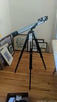Full view of Jason astronomical telescope mounted on tripod indoors with picture frames stacked nearby.