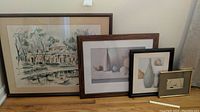 Four framed prints arranged together on floor against wall showing sizes and frames; one frame is visibly broken.