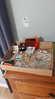 Full box view showing assorted costume jewelry including rings, earrings, bracelet, and pouches.