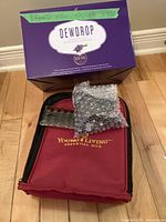 Photo of Dewdrop diffuser box on top of Young Living essential oils carrying case with sealed small oil bottles.