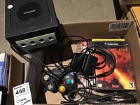 GameCube console, controller, cables and game cases in cardboard box