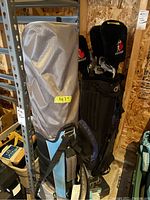 Two golf bags standing upright; one gray and blue, the other dark colored