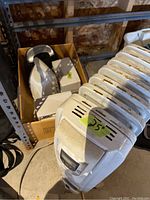 Image showing five heaters including the oil-filled radiator style and smaller box-stored electric heaters, with visible size label (25 inches) on radiator heater.