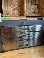 Front view showing wood top, textured grey body, and four stainless steel diamond-plate drawer fronts