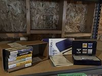 Full lot showing Nintendo DS Lite box, manuals, blue console, and black plastic game cartridge case containing multiple game cards.