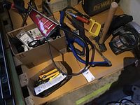 Overview photo showing Dewalt sander, hand saw, yellow hand saw, hammer, box cutters and cords.
