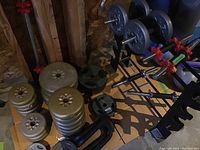 Overall view of assorted weight plates, bars, collars and storage stand