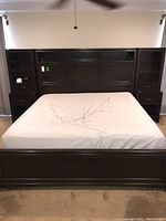 Full view of the king size bed frame including headboard and side tables, with mattress on the frame (not included in the lot)