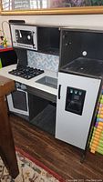 Full view of child's play kitchen with stove, microwave, and refrigerator.