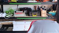 Wide view of shelves showing toolbox, extension cords, electric sander box, and metal poles