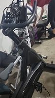 Side angle view of the MYXfitness stationary bike showing handlebar, phone/tablet holder, and part of the seat.