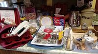Wide view of kitchenware collection including baking pans, cookie cutters, mixer, grater, and various kitchen tools arranged on a table.